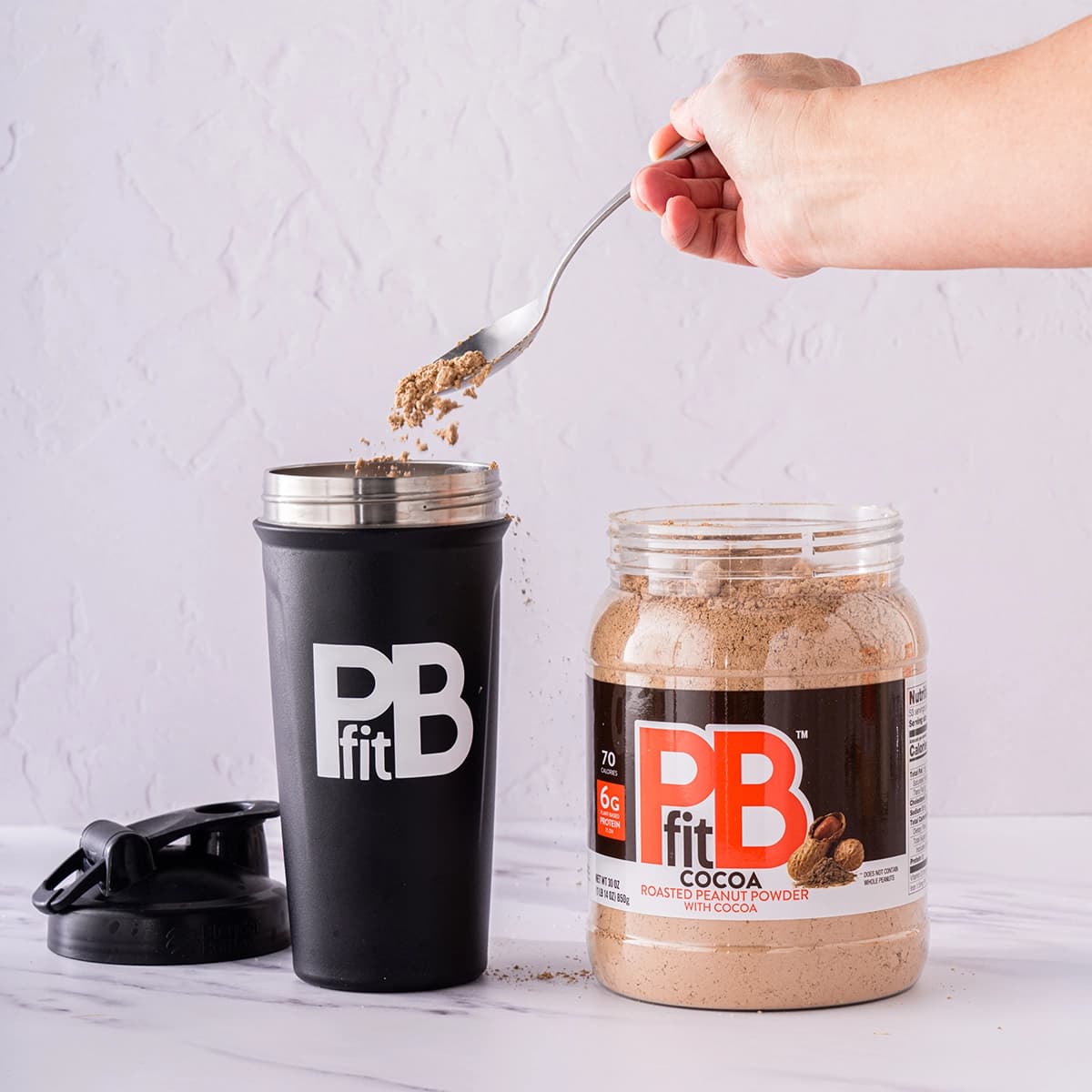 PBfit Cocoa being scopped into a blender bottle