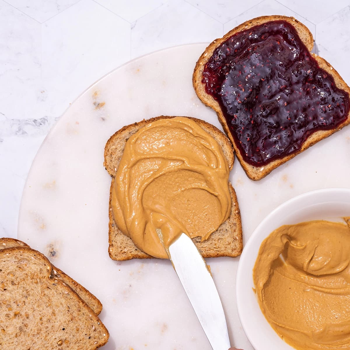 Knife spreading PBfit on bread to make a peanut butter and jelly sandwich