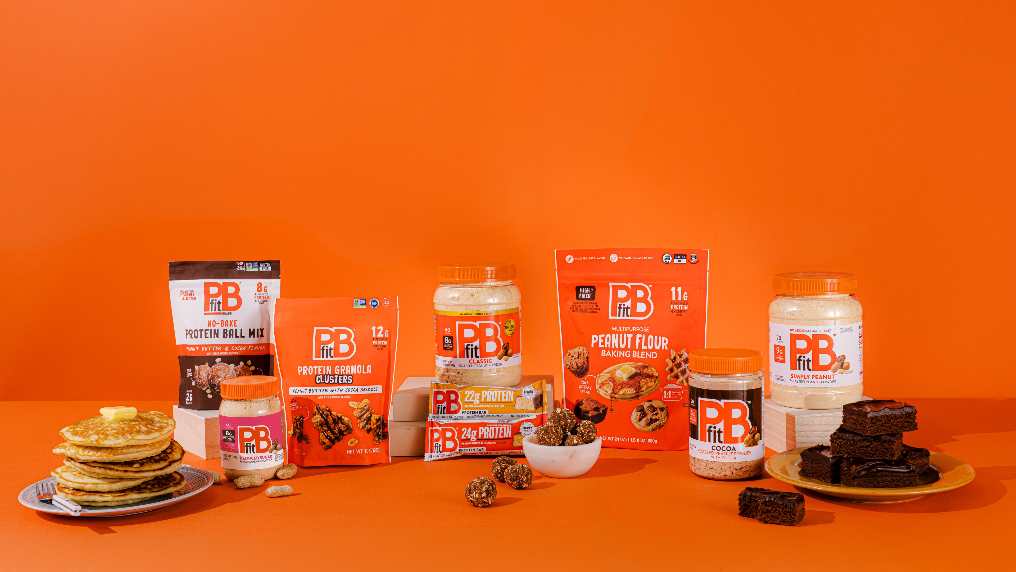 PBfit Classic surrounded by pancakes, smoothies, protein balls, cookies, and more.